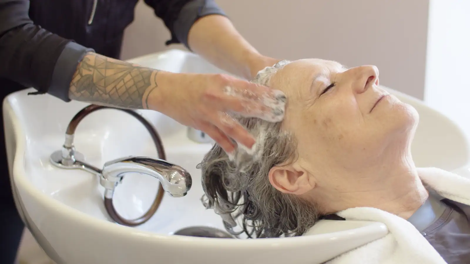 A client relaxing at the basin while her hair is washed
