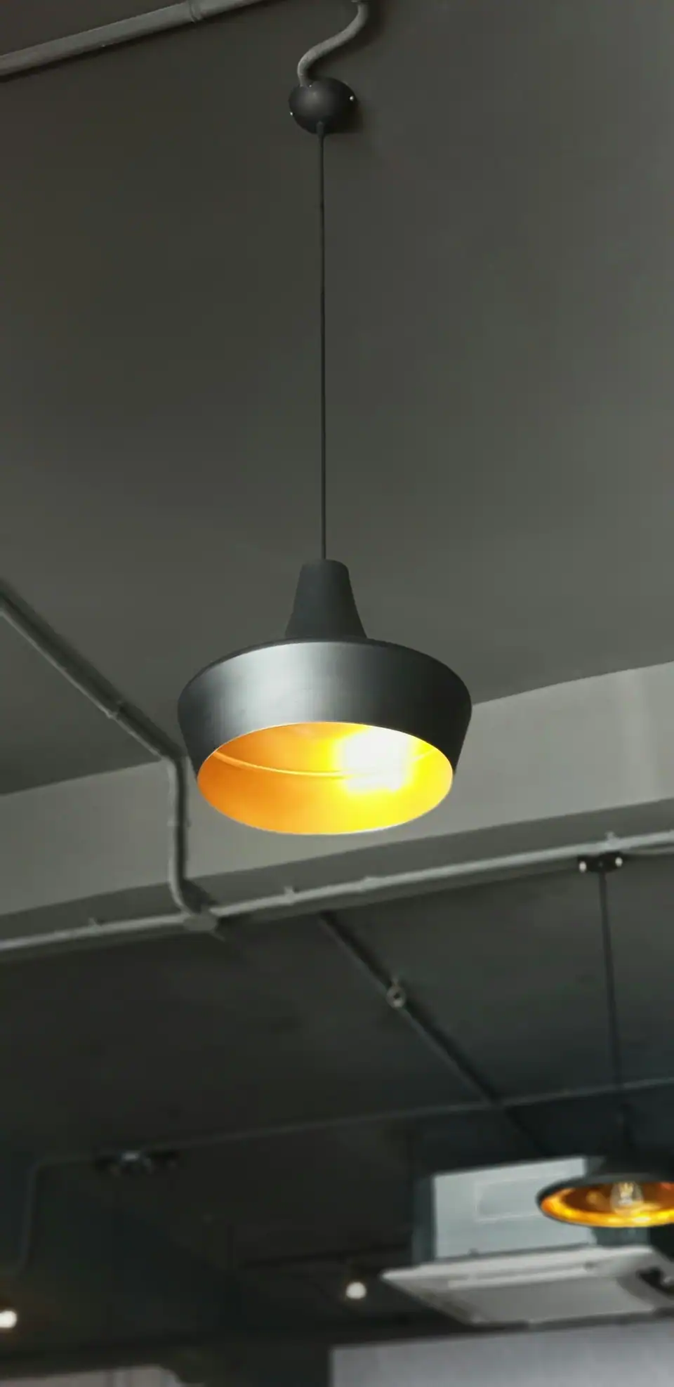 A single pendant light hanging from a dark ceiling