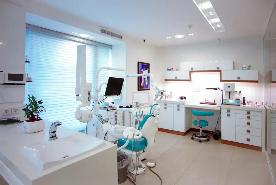 A treatment room with a window wall and a teal chair