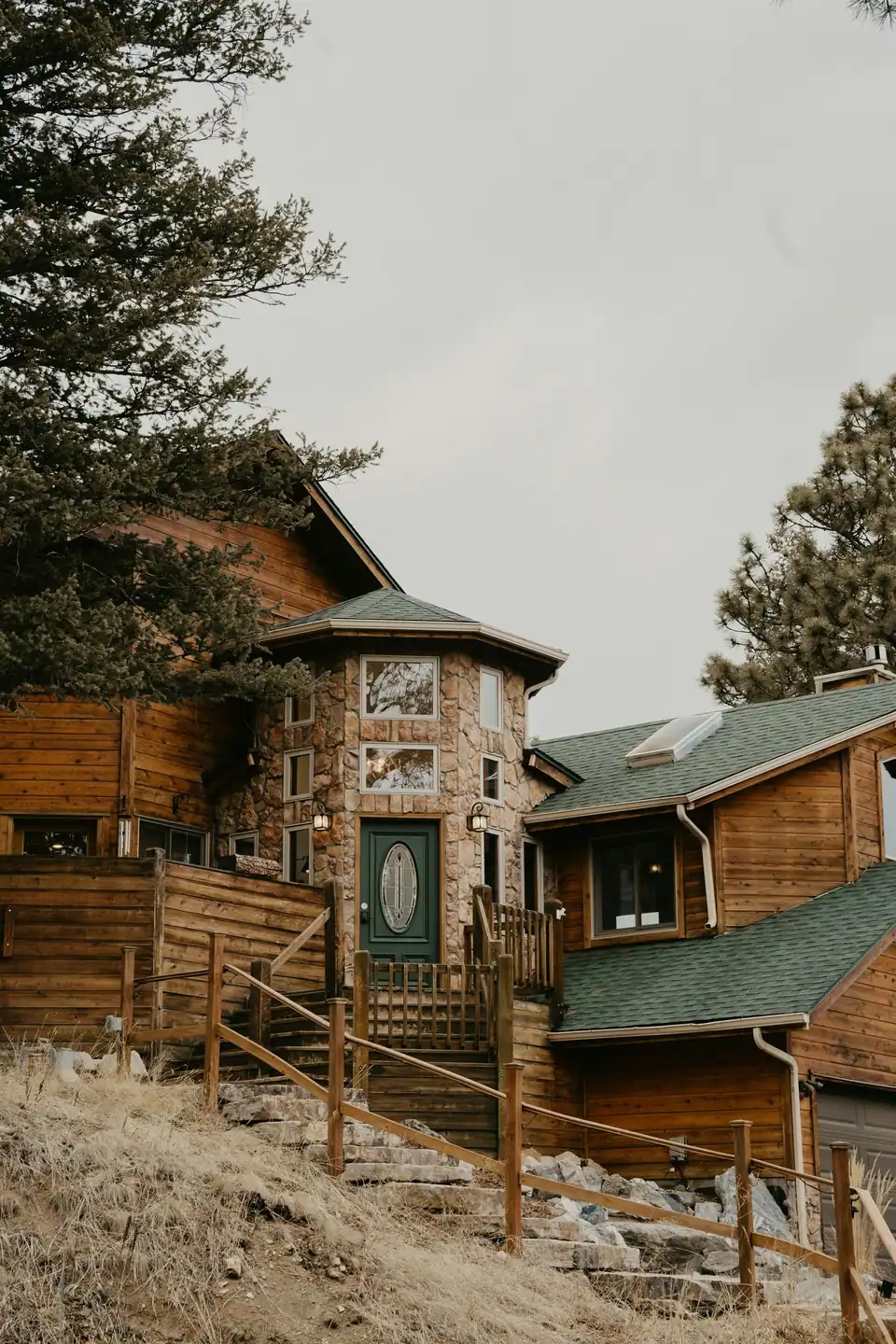 Wooden mountain home with a green roof among pines